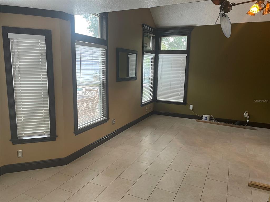 A room with tan walls, dark trim, tile flooring, and multiple windows with white blinds — 9828 BUBBLING BROOK COURT, OVIEDO, FL