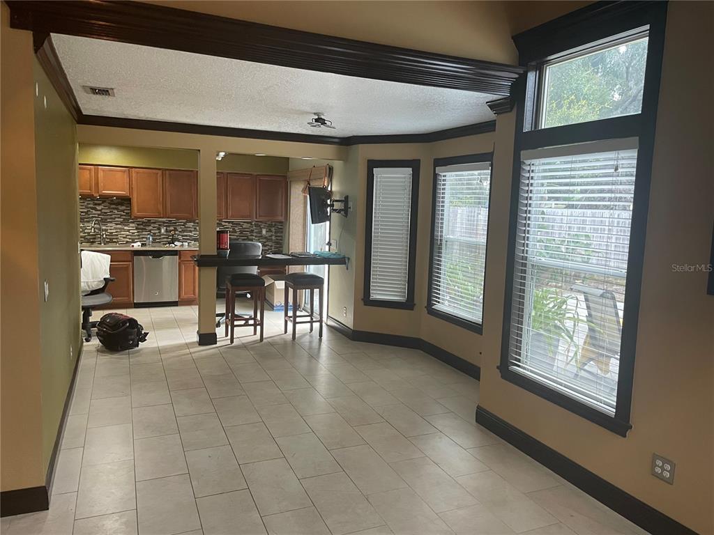 A kitchen with wood cabinets and a breakfast bar opens into a tiled dining area — 9828 BUBBLING BROOK COURT, OVIEDO, FL