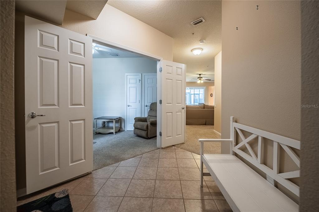 A tiled entryway features a white bench and double doors opening into a carpeted room — 2242 KINGS PALACE DRIVE UNIT 2242, RIVERVIEW, FL