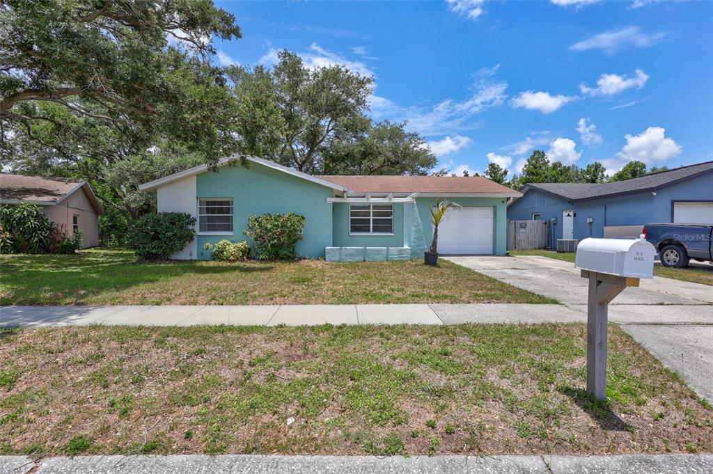 A single-story teal house with a white garage and a mailbox in the front yard — 504 7TH STREET SE, LARGO, FL