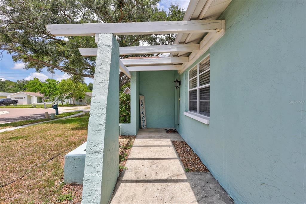 A light blue house exterior features a concrete walkway leading to a covered entryway — 504 7TH STREET SE, LARGO, FL
