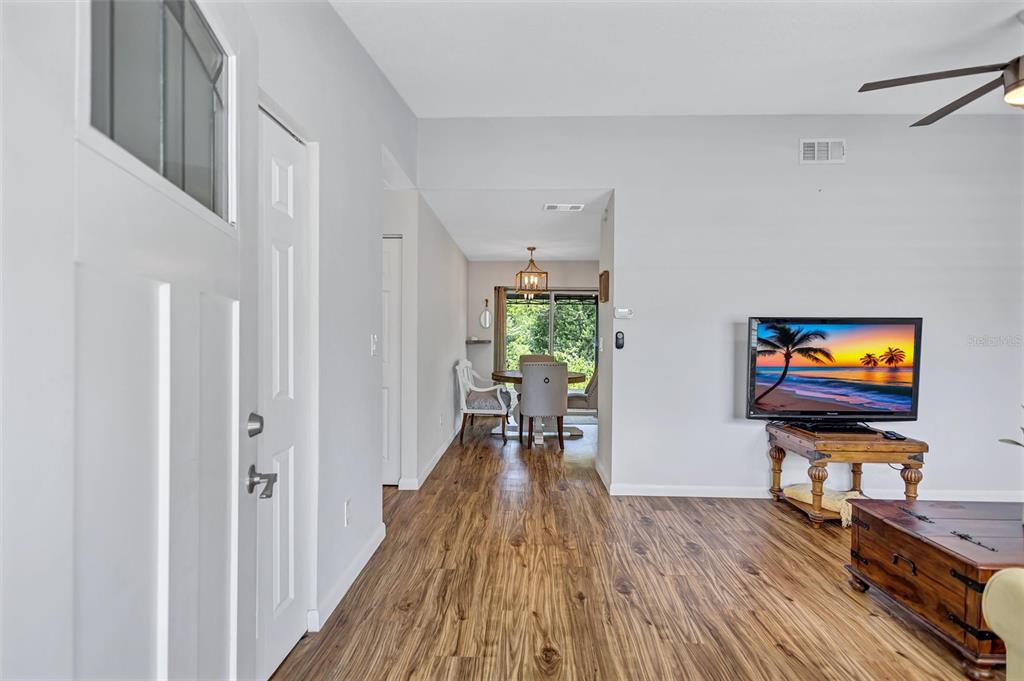 A living room with wood-look flooring leads to a dining area with a sliding door — 504 7TH STREET SE, LARGO, FL