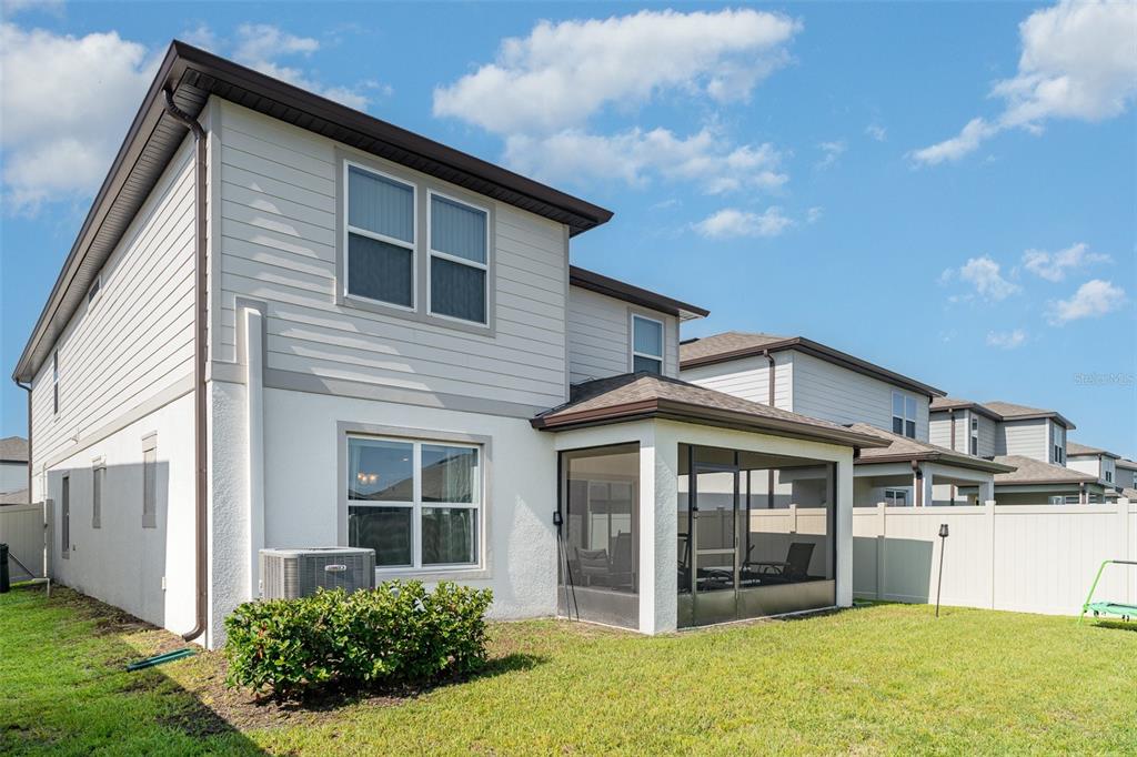 The exterior of a two-story house features a screened-in patio and a fenced backyard — 465 WATERFORD DRIVE, LAKE ALFRED, FL