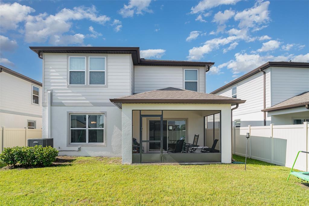 The rear exterior of a two-story house features a screened-in patio and a fenced yard — 465 WATERFORD DRIVE, LAKE ALFRED, FL