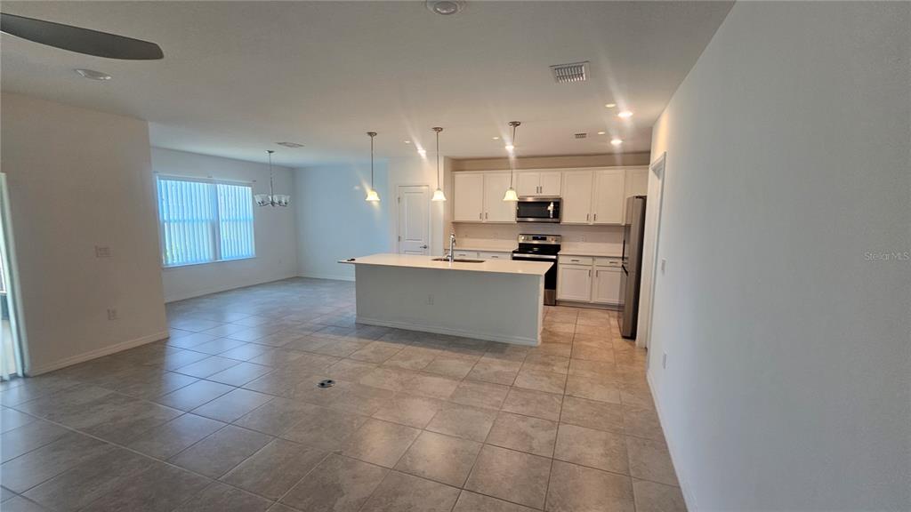 A kitchen with white cabinets, an island, and tile flooring opens into a dining area — 465 WATERFORD DRIVE, LAKE ALFRED, FL
