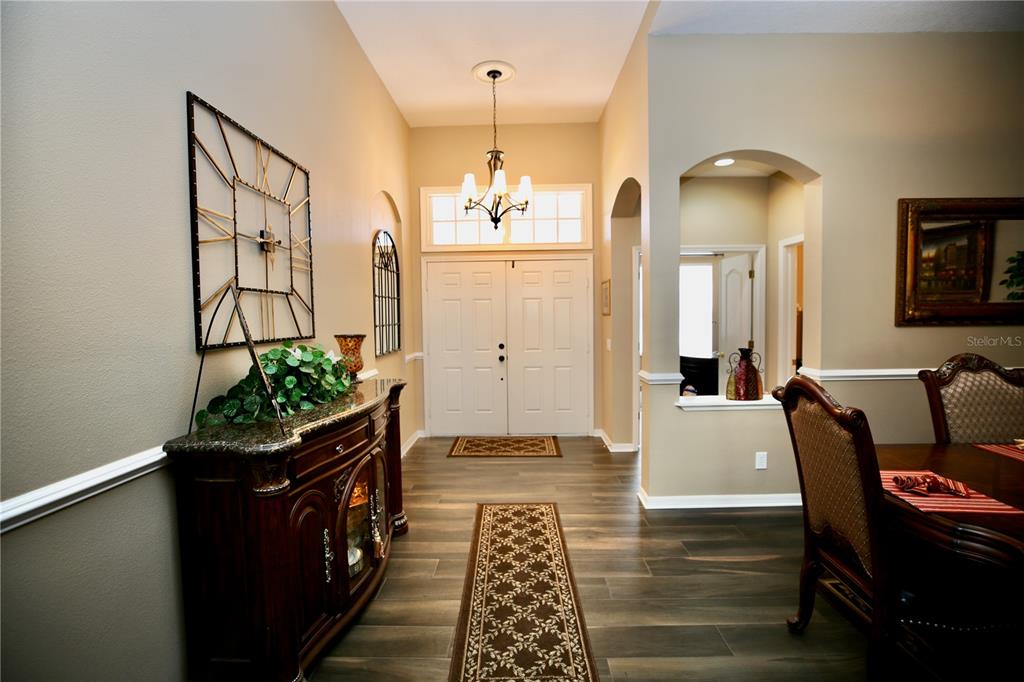 An entryway with wood-look tile flooring, a chandelier, a dark wood console, and double doors — 2410 TEA OLIVE TERRACE, VALRICO, FL