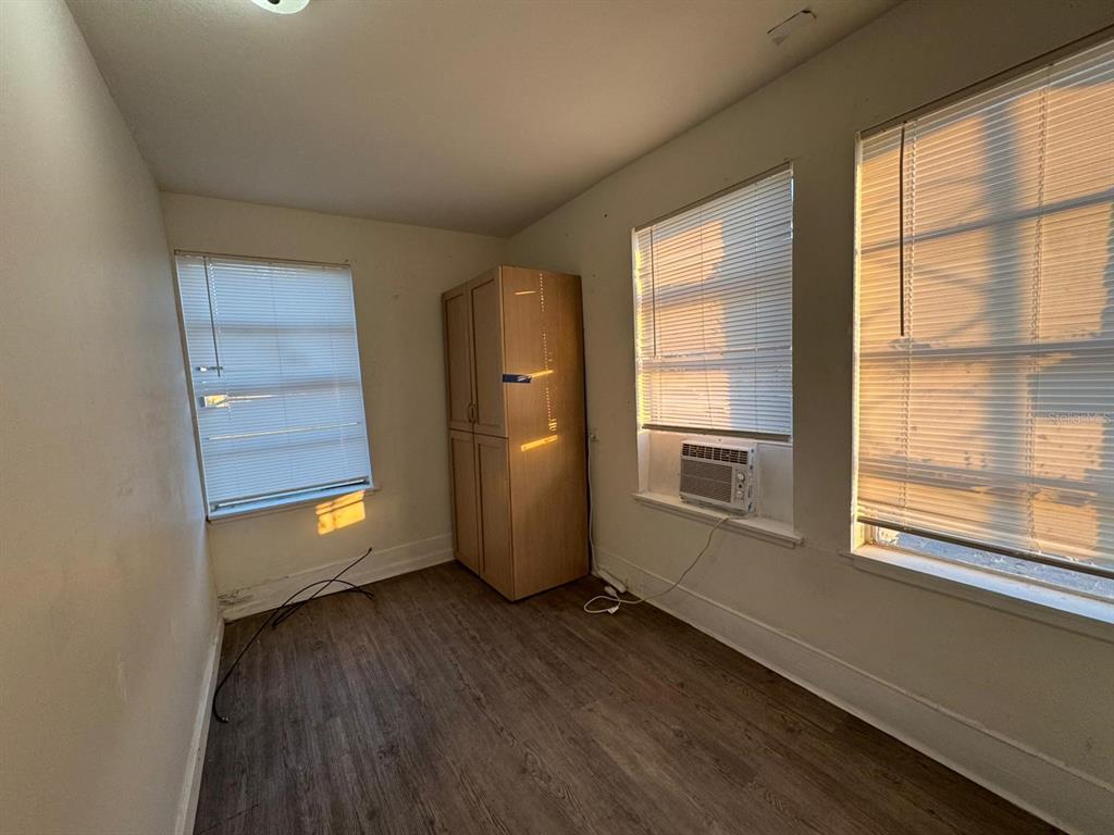 An empty room with wood-look flooring, two windows with blinds, and a tall wooden cabinet — 4201 CEPEDA STREET, ORLANDO, FL