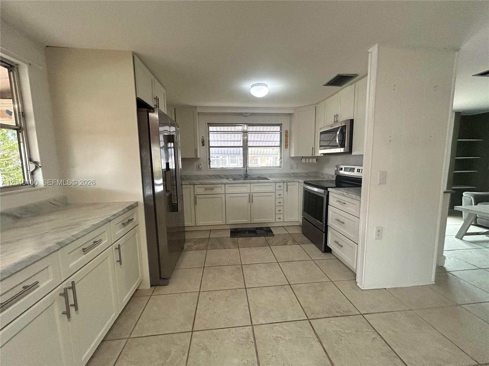 A kitchen features white cabinets, stainless steel appliances, marble-look countertops, and light tile flooring — 2341 SW 84th Ave, Davie FL 33324, DAVIE, FL