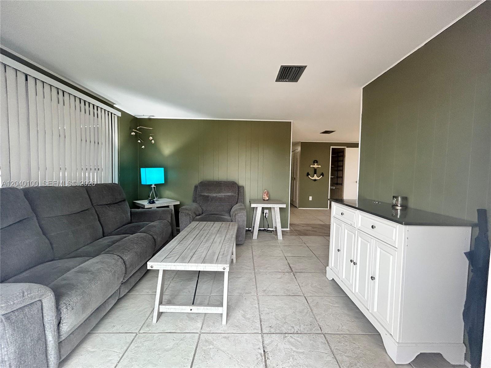 A living room features gray furniture, olive green walls, tile flooring, and a white cabinet — 2341 SW 84th Ave, Davie FL 33324, DAVIE, FL
