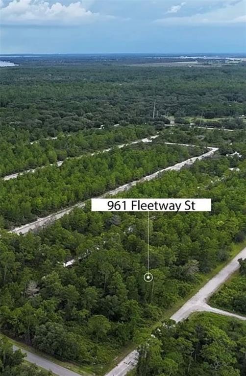 An aerial view shows a wooded, undeveloped lot located along a dirt road — 961 FLEETWAY STREET, LAKE PLACID, FL