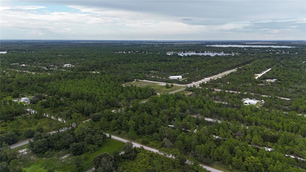 An aerial view shows a rural landscape with scattered houses, dense trees, and paved roads — 961 FLEETWAY STREET, LAKE PLACID, FL