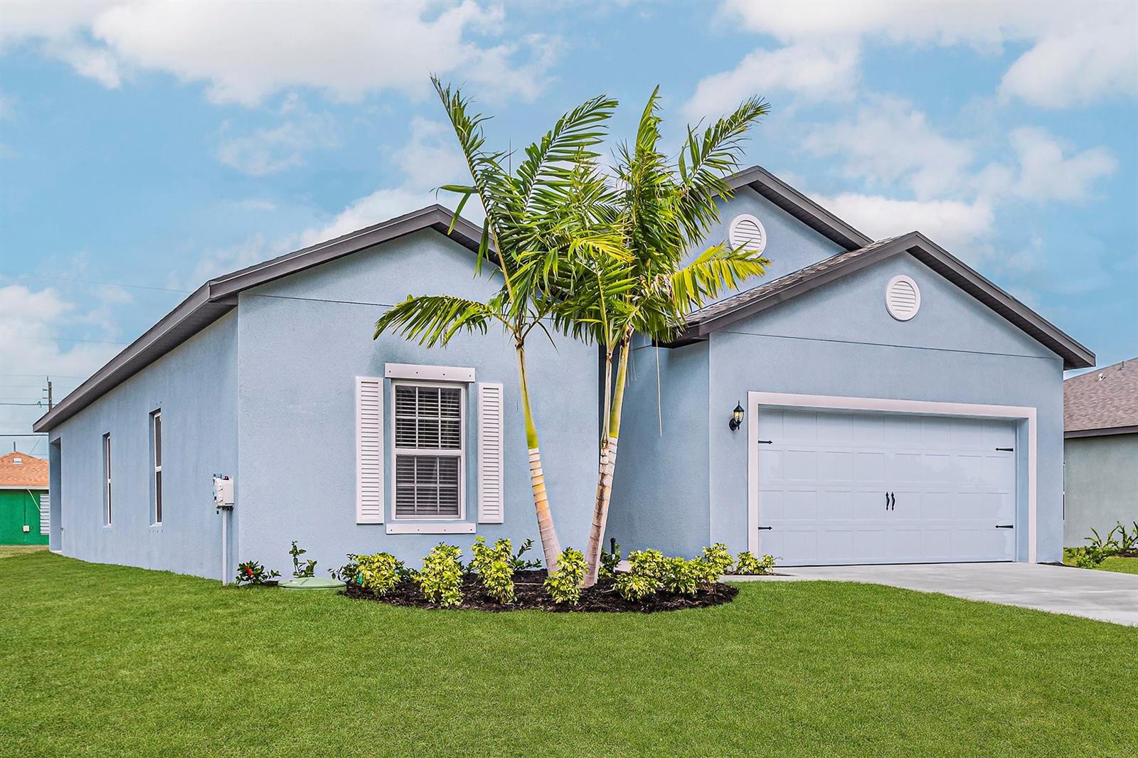 A light blue single-story house with a two-car garage and a palm tree in front — 7705 105th Court, Vero Beach FL 32967, VERO BEACH, FL
