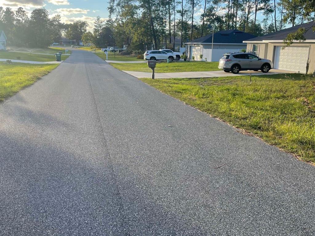 A residential street view showing a paved road, suburban houses, and parked vehicles — 0 SW 157TH STREET, OCALA, FL