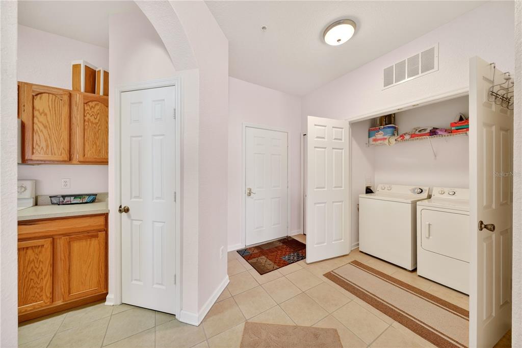 A laundry room with tile flooring, wooden cabinets, and a washer and dryer in a closet — 2788 ALMATON LOOP UNIT 404, KISSIMMEE, FL