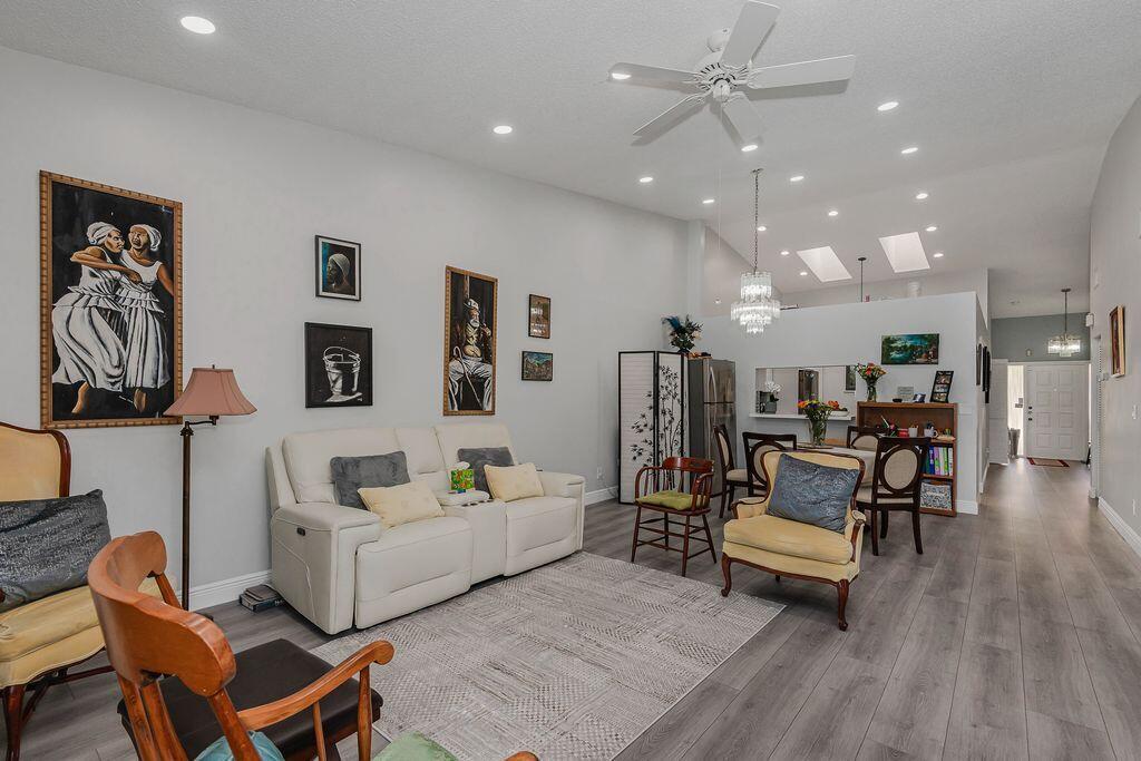 A living room with light gray walls, wood-look flooring, a white sofa, and vaulted ceilings — 3459 Inverrary W # 3459, Lauderhill FL 33319, LAUDERHILL, FL