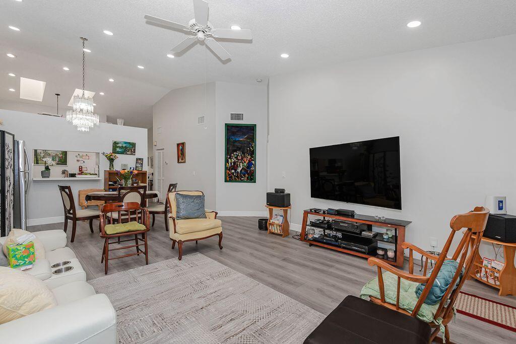 A living room with gray wood-look flooring, a large television, and a dining area — 3459 Inverrary W # 3459, Lauderhill FL 33319, LAUDERHILL, FL