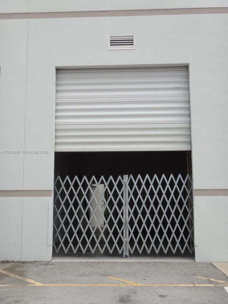 A white roll-up door is partially open above a metal security gate at a warehouse entrance — 1365 NW 98th Ct # 5, Doral FL 33172, DORAL, FL