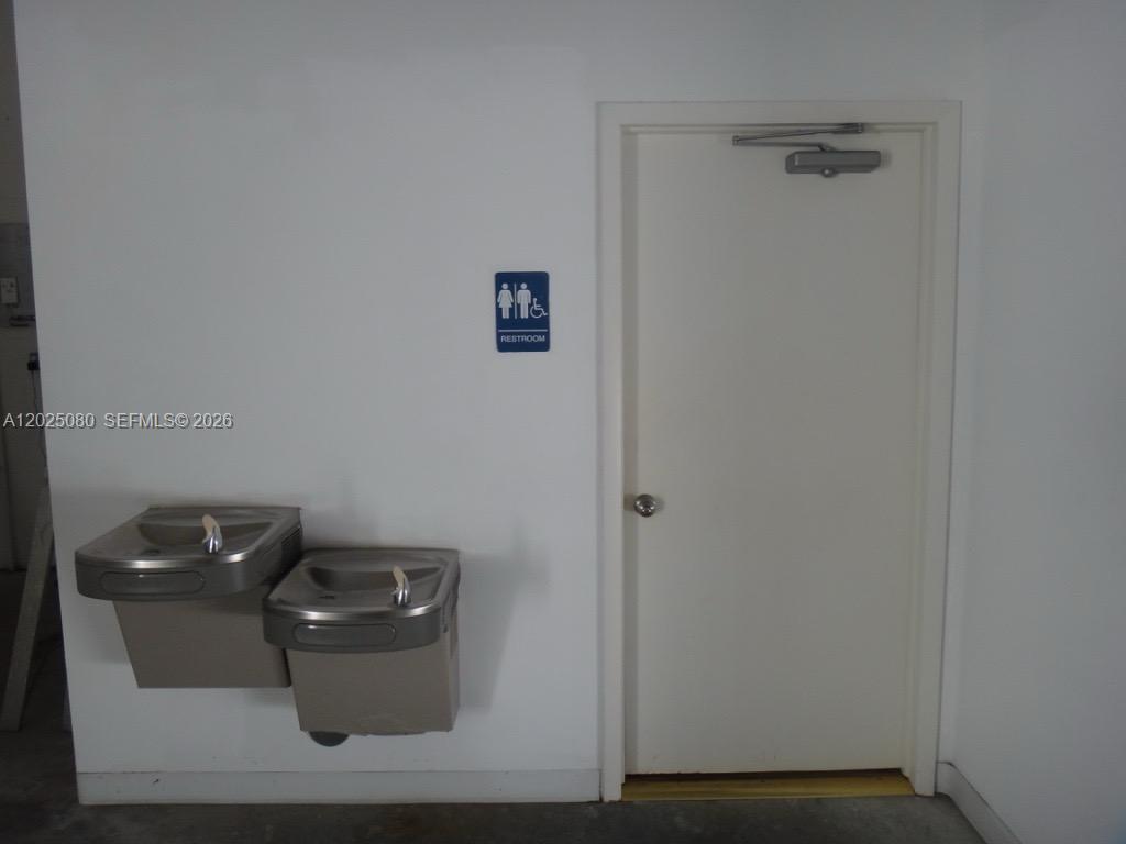 A white wall features two stainless steel water fountains next to a closed restroom door — 1365 NW 98th Ct # 5, Doral FL 33172, DORAL, FL