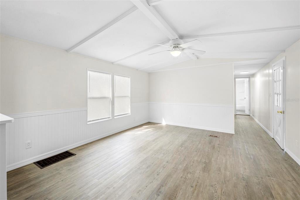 A bright living room features white beadboard wainscoting, light wood-look flooring, and a ceiling fan — 8110 W ROSELLA COURT, CRYSTAL RIVER, FL