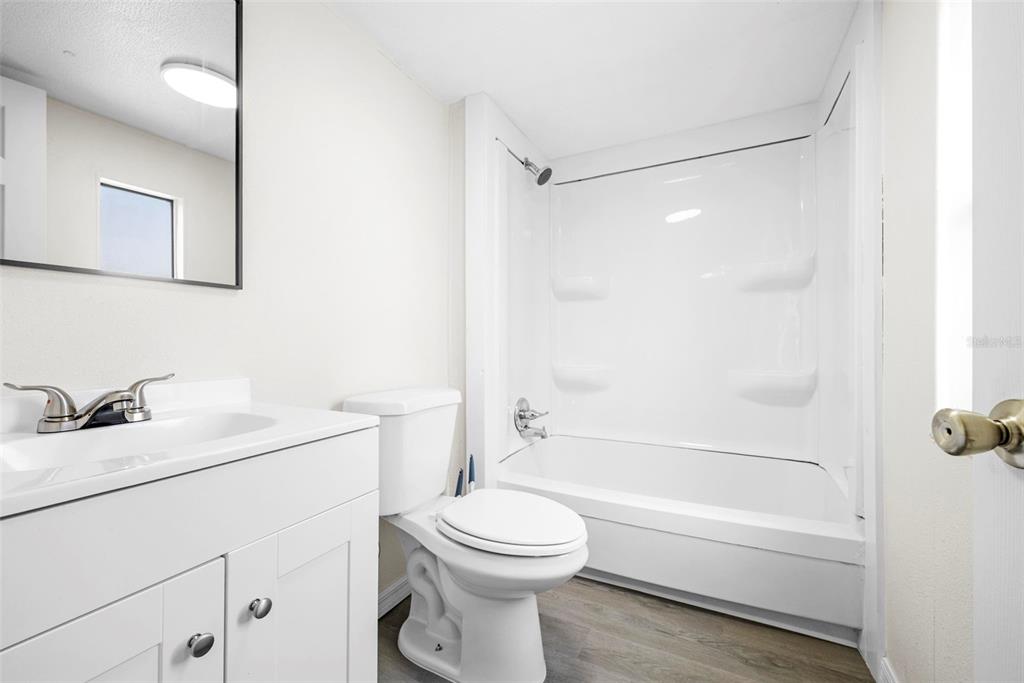 A bathroom features a white vanity, a toilet, and a shower-tub combination with white walls — 8110 W ROSELLA COURT, CRYSTAL RIVER, FL