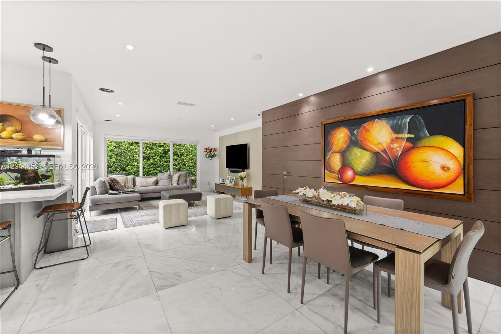 A modern open-concept living and dining area features white marble floors and wood-paneled walls — 721 Bird Rd, Coral Gables FL 33146, CORAL GABLES, FL
