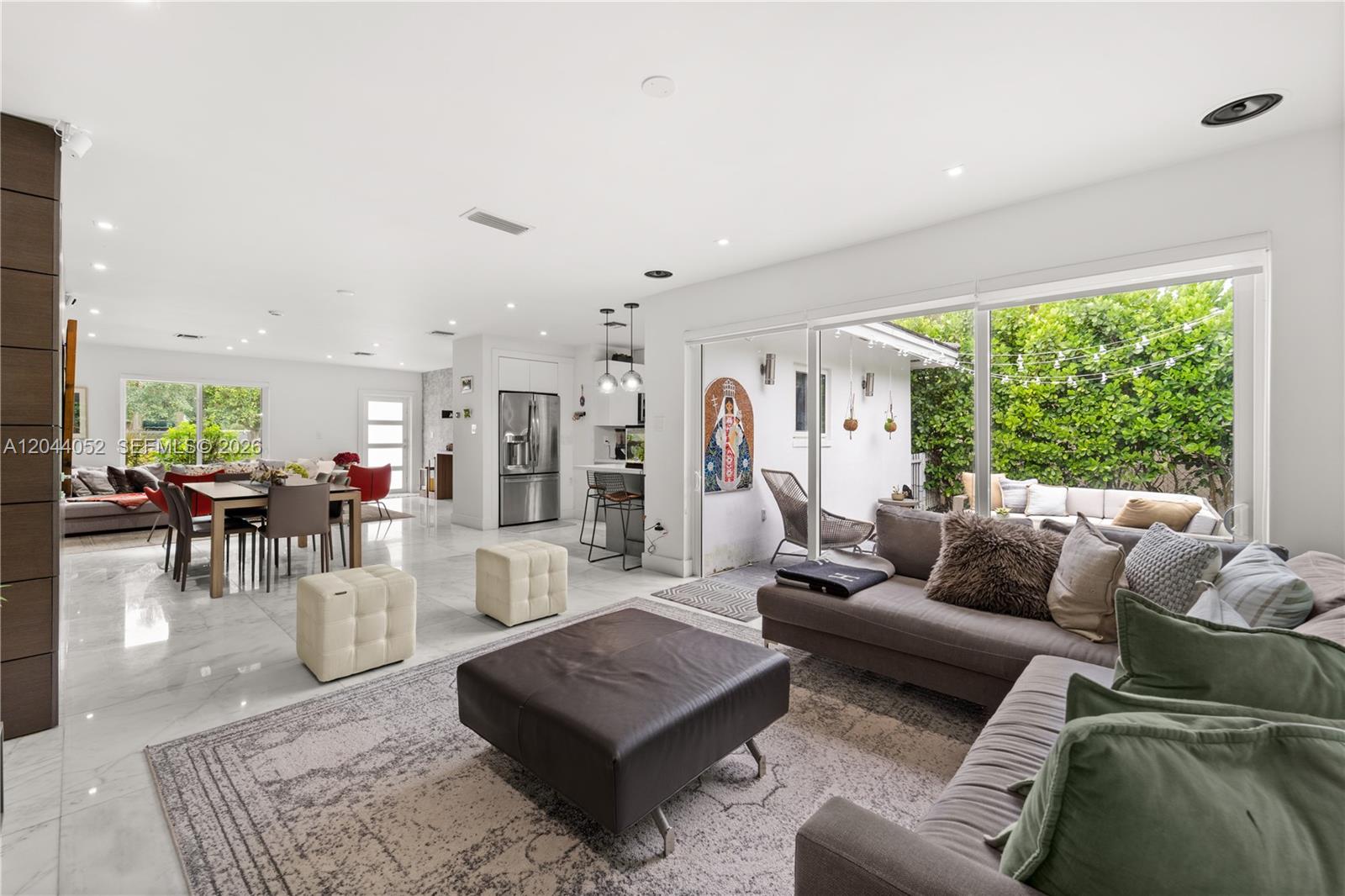 An open-concept living and dining area features white tile floors, a modern kitchen, and sliding glass doors — 721 Bird Rd, Coral Gables FL 33146, CORAL GABLES, FL