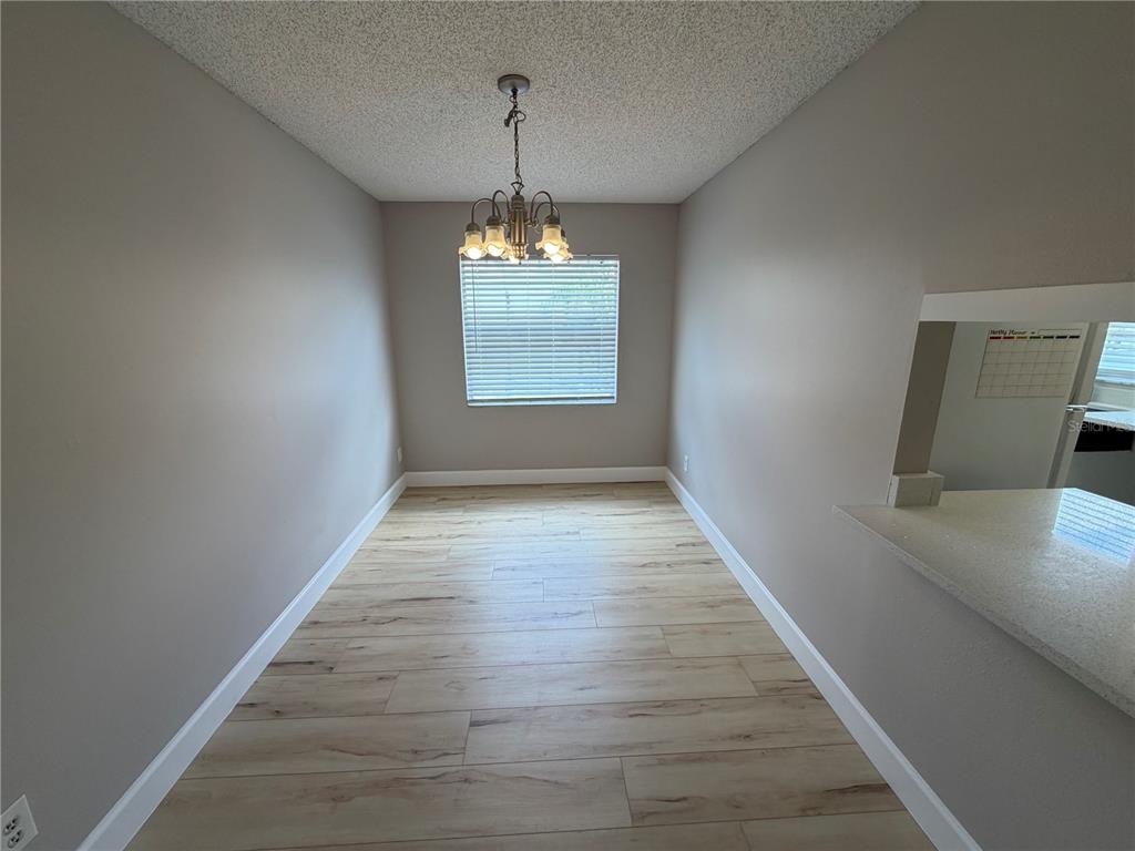 A dining area features light wood-look flooring, a chandelier, and a window with blinds — 4160 PERSHING POINTE PLACE UNIT 3, ORLANDO, FL