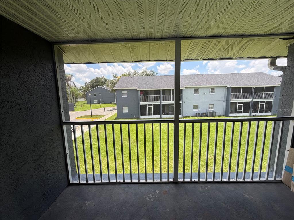 A screened-in balcony overlooks a grassy courtyard and a neighboring apartment building — 4160 PERSHING POINTE PLACE UNIT 3, ORLANDO, FL