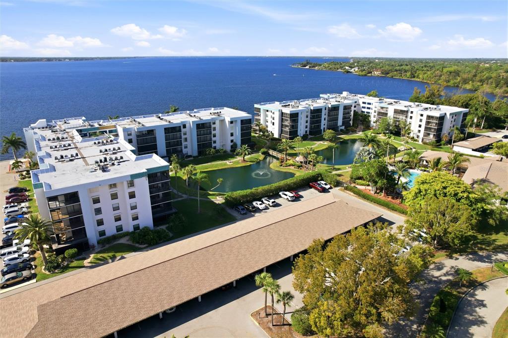 An aerial view shows multi-story apartment buildings, a large lake, and a covered parking area — 3460 N KEY DRIVE UNIT 407, NORTH FORT MYERS, FL
