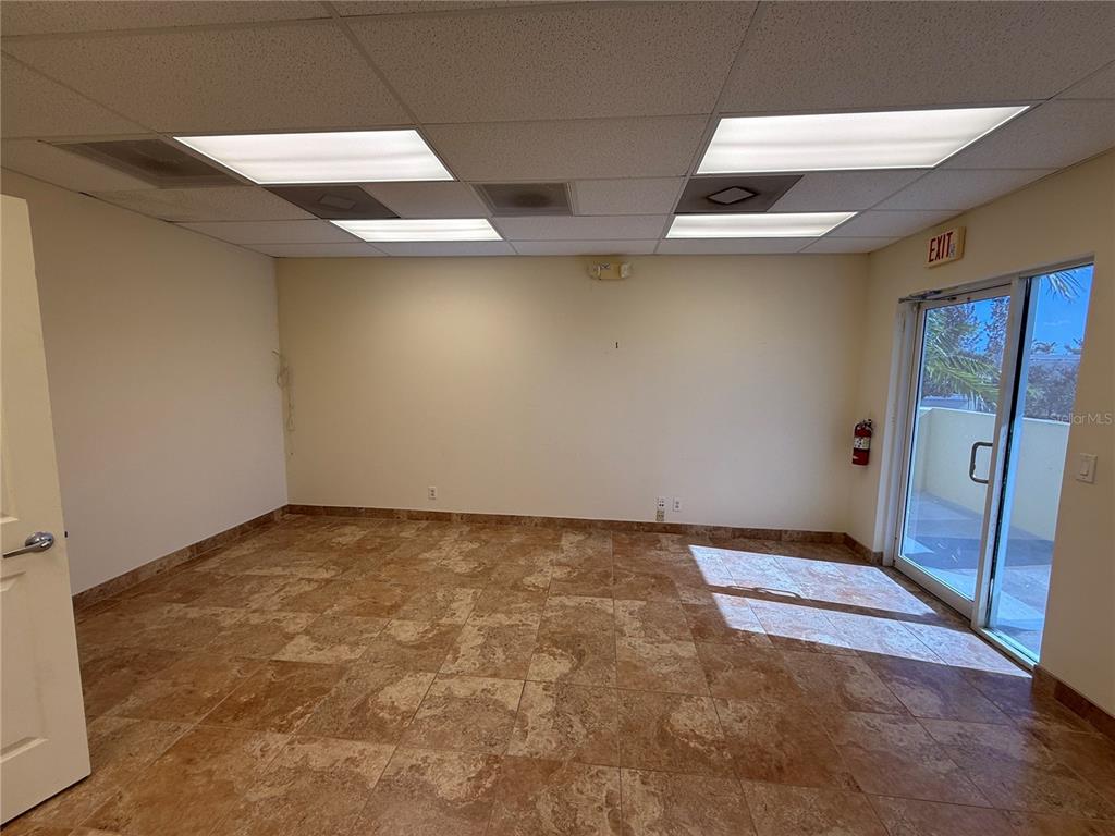 An empty office room features tan tile flooring, a drop ceiling, and a sliding glass door — 2755 VISTA PARKWAY UNIT I-2, WEST PALM BEACH, FL