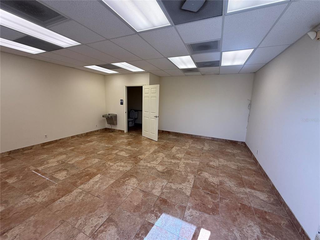 An empty office space features tan tile flooring, a drop ceiling, and an attached restroom — 2755 VISTA PARKWAY UNIT I-2, WEST PALM BEACH, FL