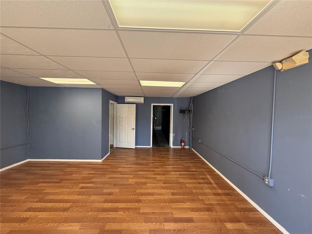 An empty room features blue walls, wood-look flooring, a drop ceiling, and two doorways — 2755 VISTA PARKWAY UNIT I-2, WEST PALM BEACH, FL