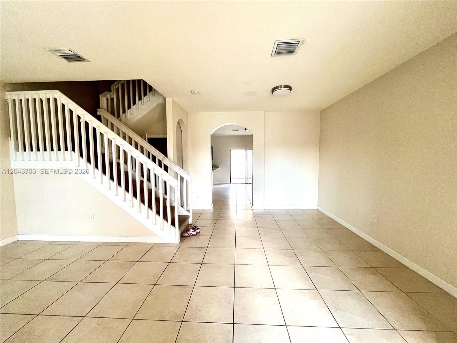 An interior view shows a tiled living area with a staircase and an arched doorway — 9271 W 33rd Ln # 9271, Hialeah FL 33018, HIALEAH, FL