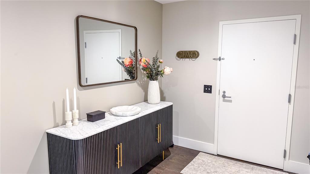 A modern entryway features a marble-topped black fluted console table, a mirror, and a white door — 175 1ST STREET S UNIT 1108, ST PETERSBURG, FL