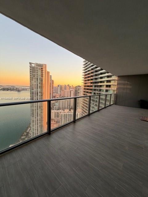 A spacious balcony with tile flooring overlooks a city skyline and water at sunset — 650 NE 32nd St # 4406, Miami FL 33137, MIAMI, FL