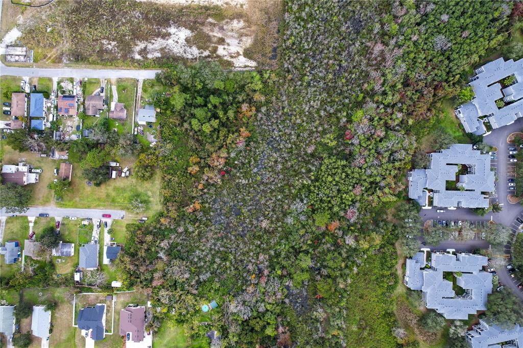 An aerial view shows a wooded lot situated between a residential neighborhood and apartment buildings — 2207 CALLOWAY DRIVE, ORLANDO, FL