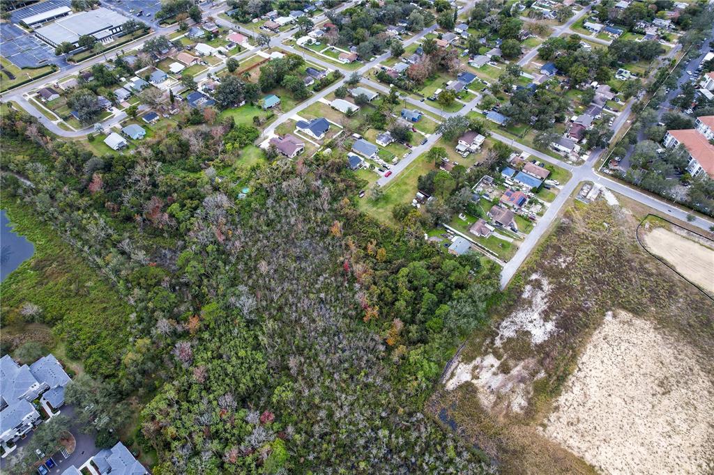 An aerial view shows a wooded lot bordered by residential streets and a cleared field — 2207 CALLOWAY DRIVE, ORLANDO, FL