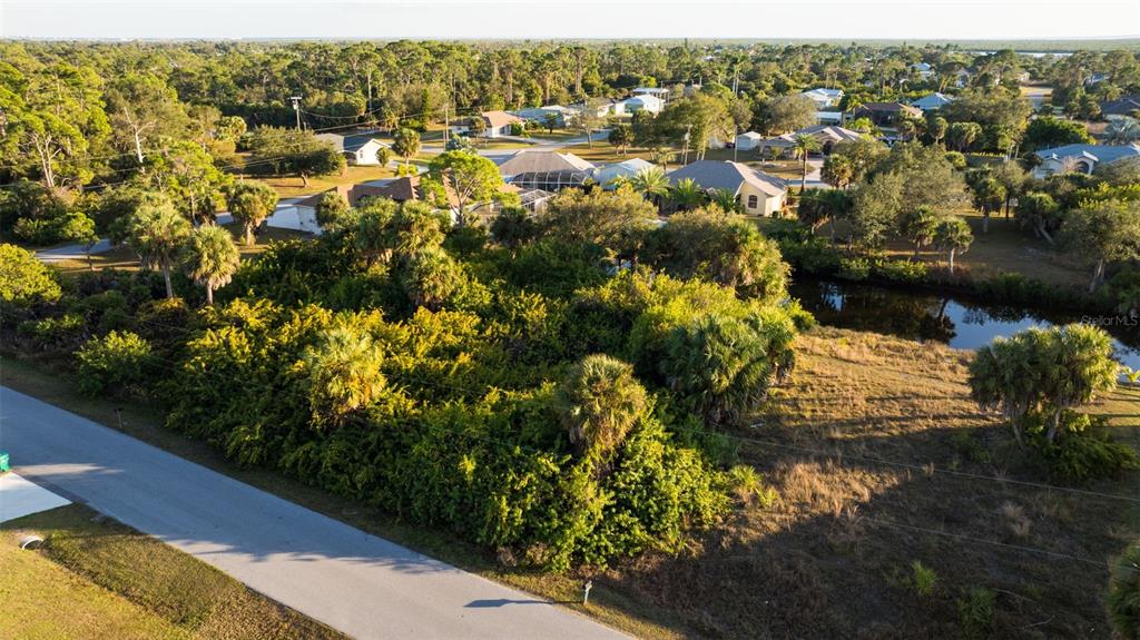 An aerial view shows a vacant, tree-covered lot next to a small canal and road — 17192 SABRINA CIRCLE, PORT CHARLOTTE, FL