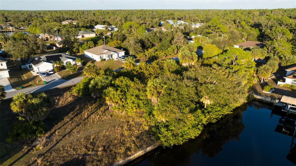 An aerial view shows a vacant, wooded residential lot situated along a canal — 17192 SABRINA CIRCLE, PORT CHARLOTTE, FL