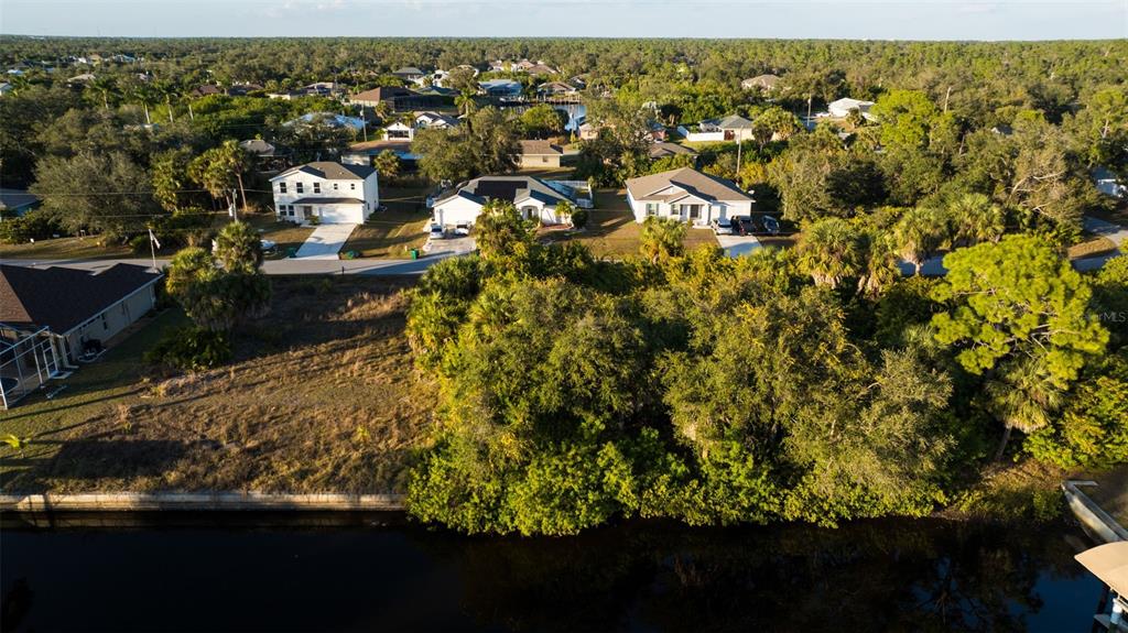An aerial view shows a vacant, grassy lot bordering a canal near several suburban houses — 17192 SABRINA CIRCLE, PORT CHARLOTTE, FL