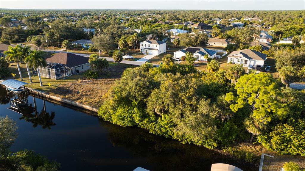 An aerial view shows a canal-front residential property with a boat lift and surrounding homes — 17192 SABRINA CIRCLE, PORT CHARLOTTE, FL