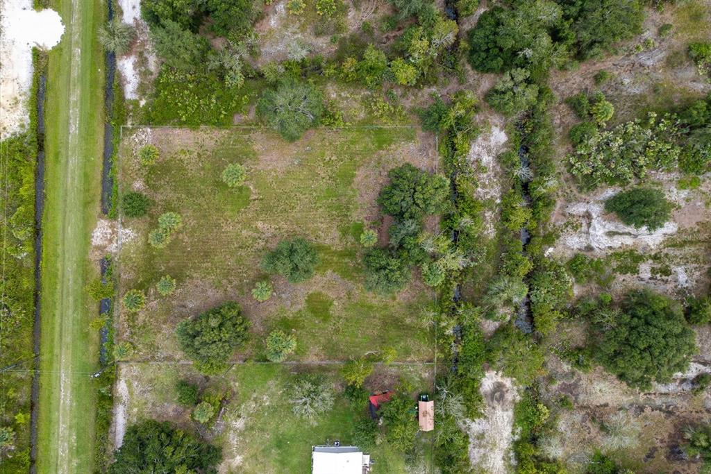 An aerial view shows a rectangular, grassy plot of land bordered by trees and vegetation — 17128 NW 266TH STREET, OKEECHOBEE, FL