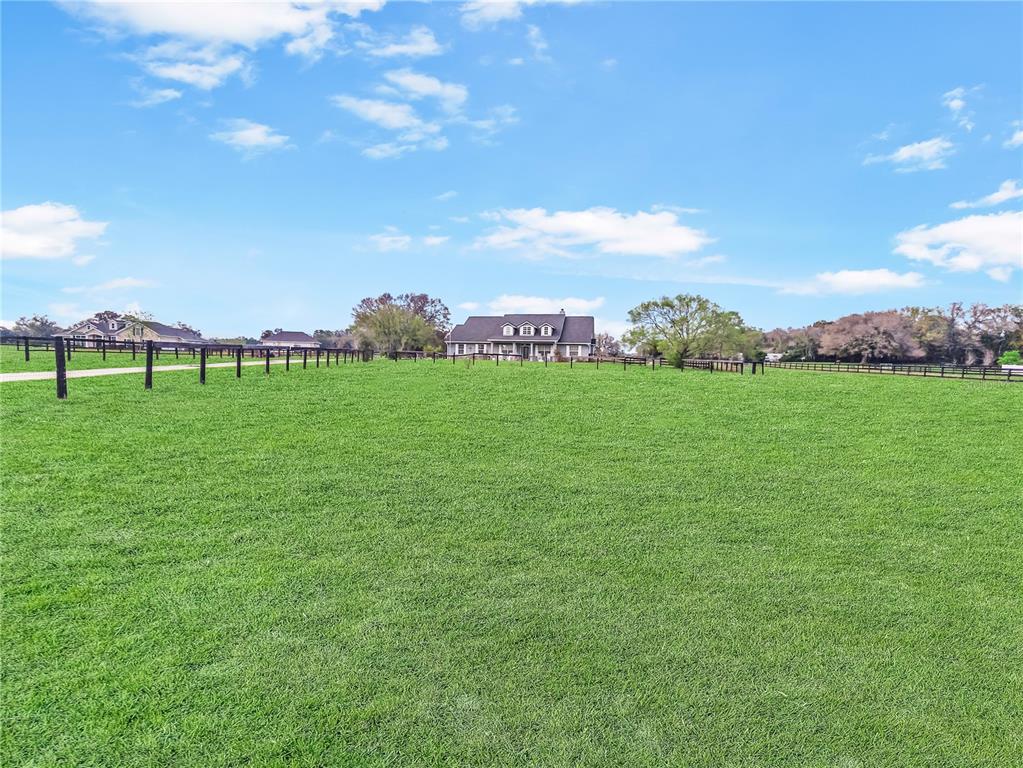 A large green pasture is enclosed by black fencing with a house in the distance — 5725 NE 31ST TERRACE, OCALA, FL