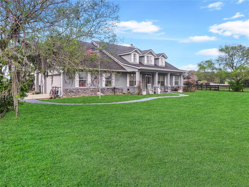 A gray house with a stone base, front porch, and three dormers sits on grass — 5725 NE 31ST TERRACE, OCALA, FL