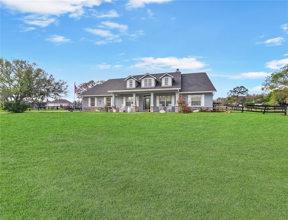 A gray single-story house with three dormers sits behind a large, expansive green lawn — 5725 NE 31ST TERRACE, OCALA, FL