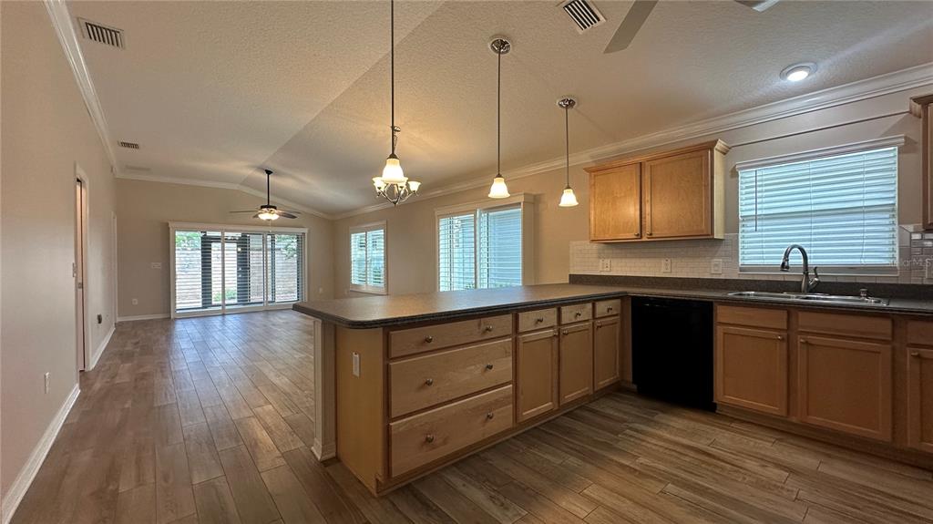 A kitchen with light wood cabinets, dark countertops, and an island opens to a living area — 724 YAGER LANE, THE VILLAGES, FL