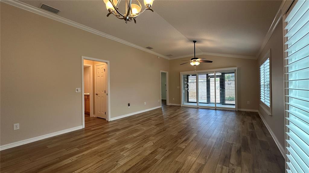A spacious living room features wood-look flooring, a ceiling fan, and sliding glass patio doors — 724 YAGER LANE, THE VILLAGES, FL