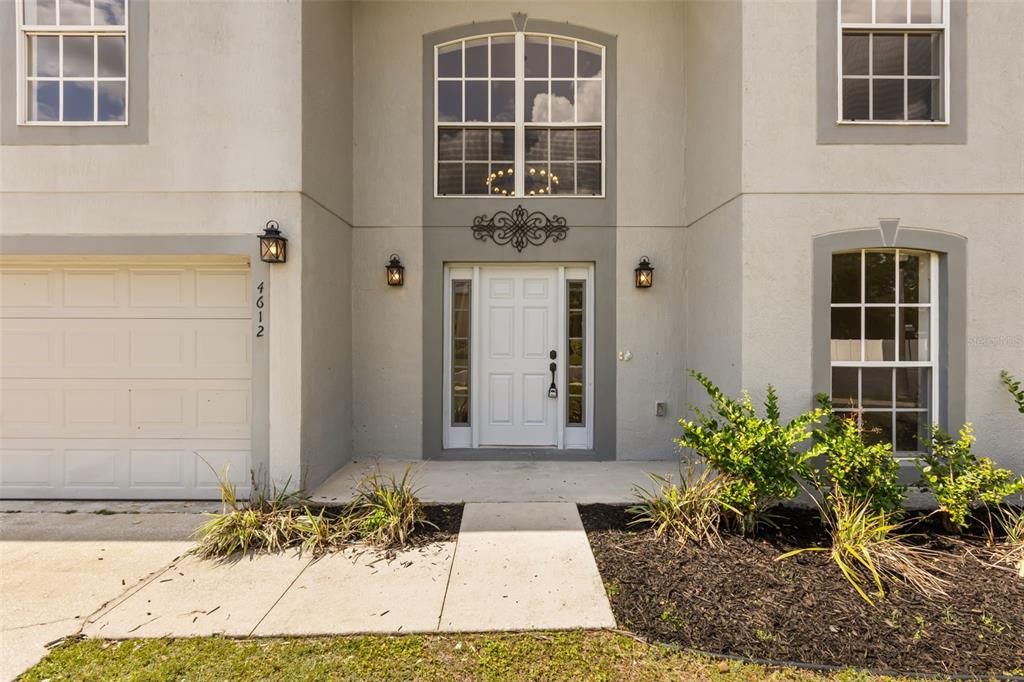 The exterior of a two-story house features a white front door, garage, and arched windows — 4612 SE 31ST PLACE, OCALA, FL