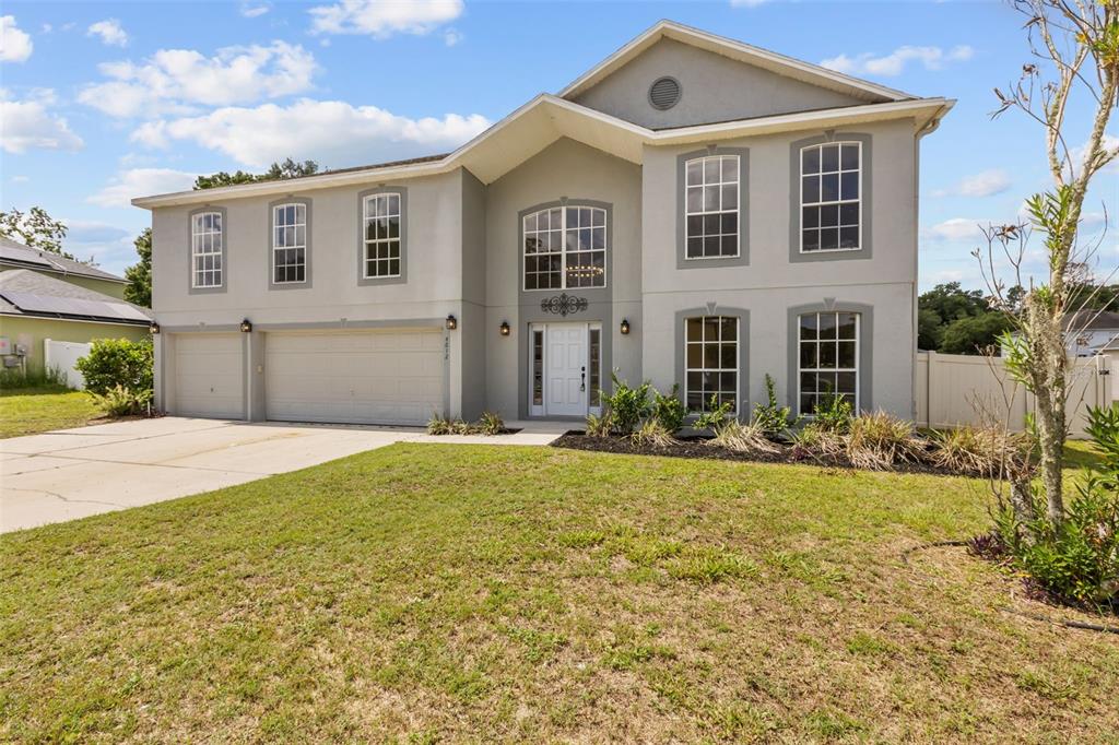 A two-story house with a gray stucco exterior, a three-car garage, and a front lawn — 4612 SE 31ST PLACE, OCALA, FL