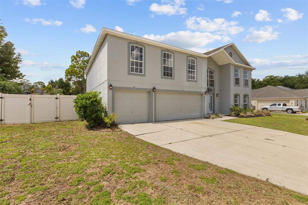 A two-story house with a three-car garage and a concrete driveway under a blue sky — 4612 SE 31ST PLACE, OCALA, FL